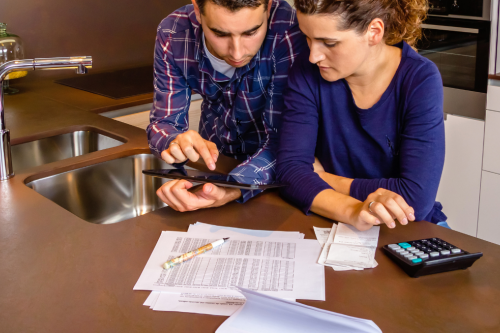 Casal a analisar documentos financeiros e faturas antes de decidir sobre o crédito habitação